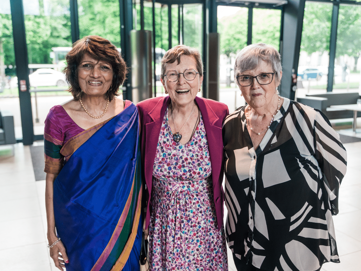 Professor Terry Threadgold, smiling broadly, with her arms around Professor Meena Upadhyaya and Professor Sheila Hunt.